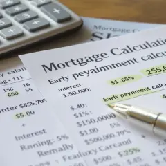 Calculatrice et documents financiers. On y voit des calculs de prêt hypothécaire, des taux d'intérêt et des frais de remboursement anticipé credit agricole.