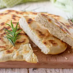 Una crescia umbra appena sfornata, dorata e profumata, con un rametto di rosmarino fresco.