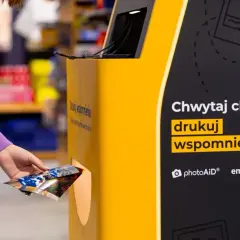 Ręka wyjmuje wydrukowane zdjęcia z automatu. Teraz wiesz, jak wywołać zdjęcia w Empiku i drukować wspomnienia.
