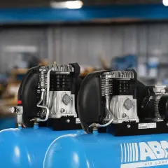 Dos compresores de aire ABAC con motor eléctrico y cabezal de pistón, un tipo de compresor reciprocante, listos para trabajar.
