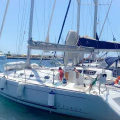 Barca a vela bianca ormeggiata, con scritte "17 FIRST" e "Finistère". Dettagli tecnici e mare calmo.