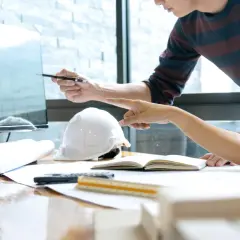 Deux architectes discutent d'un plan sur un écran, utilisant un système de gestion de contenu d'entreprise pour organiser leurs documents.