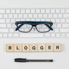 Wpis na bloga matura angielski: klawiatura, okulary i kostki z napisem BLOGGER.