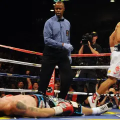 A boxer lies on the canvas as the referee stands over him. The victor, Manny Pacquiao, walks away, his red glove raised. Can you push in boxing? Yes, this is the result of a powerful punch.