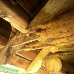 Poutre en bois vermoulue, soutenue par des tiges filetées. Le prix pour changer une poutre pourrie est une préoccupation majeure pour la rénovation.