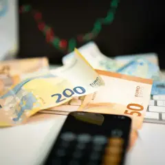 Euro banknoty na klawiaturze, telefon i wykres giełdowy sugerują inwestowanie w waluty.