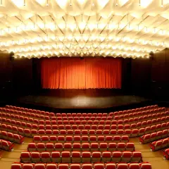 Leere rote Sitze im **Theater und Konzerthaus Solingen** warten auf Besucher. Die Bühne ist mit einem roten Vorhang verdeckt.