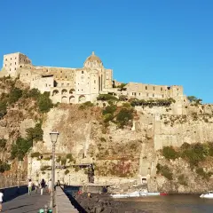 Il Castello Aragonese di Ischia, con i suoi orari e prezzi da scoprire, domina la roccia. Un ponte conduce all'imponente fortezza.