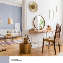 Jasny salon z sofą i stolikiem kawowym. Obok toaletka z lustrem i krzesłem. Jaki kolor pasuje do białego? Jasne drewno i pastelowy błękit tworzą przytulną atmosferę.