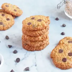 Deliciosas galletas de avena y chocolate, apiladas y esparcidas, con chispas de chocolate y avena en un frasco.