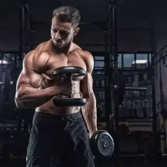 Mężczyzna ćwiczy biceps z hantlami. Ile serii na biceps w tygodniu? To pytanie zadaje sobie wielu trenujących.