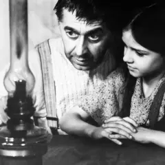 Ein Mann und ein Mädchen beugen sich über eine Öllampe. Ein Ausschnitt aus einem DDR-Film, vielleicht in der Mediathek zu finden.