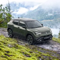 Grön Suzuki Vitara med automatisk växellåda kör på en mossig, stenig sluttning i regn.
