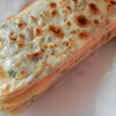 Gozleme épinard, une crêpe turque dorée et pliée, garnie d'épinards frais et savoureux.