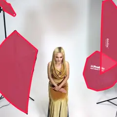 Modelka w złotej sukni, otoczona różnymi rodzajami oświetlenia w fotografii studyjnej.
