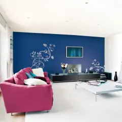 Un salone moderno con divano fucsia e parete blu con decorazioni floreali. Idee per come pitturare un salone con stile.