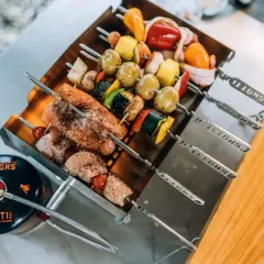 Leckere Spieße mit Lachs, Hähnchen und Gemüse warten auf das Grillen mit Gasgrill. Daneben eine Gasflasche.