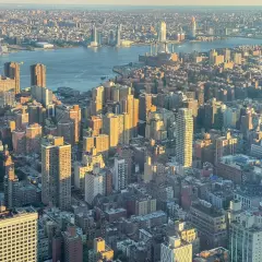 Widok z lotu ptaka na Manhattan i Brooklyn o zachodzie słońca. Rzeka Hudson rozdziela dwa miasta, a światła miasta zaczynają migotać.