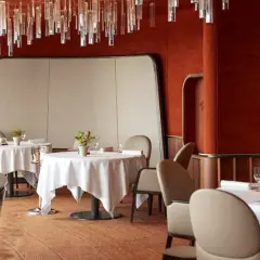 Interni eleganti di ristoranti 2 stelle Michelin Italia, con tavoli apparecchiati e un'installazione luminosa di cristallo.