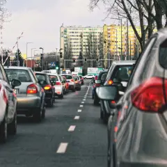 Korki miejskie, gdzie zasady jazdy samochodem po mieście wymagają cierpliwości. Długi rząd aut na drodze, budynki w tle.