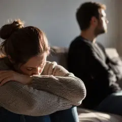 Smutna kobieta zamyka się w sobie, podczas gdy mężczyzna odwraca się od niej. Cienie przeszłości niszczą związek, tworząc dystans.
