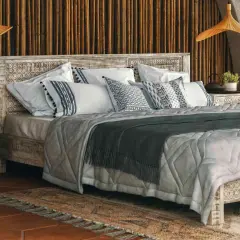 A cozy bedroom with a carved wooden bed, featuring decorative pillow shams. Can you sleep on pillow shams? Yes, they add comfort and style.