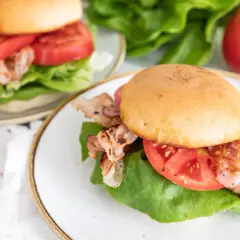Dwa pyszne BLT na talerzach, z chrupiącym bekonem, soczystymi pomidorami i świeżą sałatą. Idealne na szybki lunch.