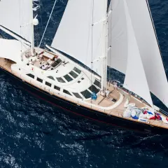 Lussuoso yacht a vela, forse il yacht Berlusconi, solca le acque blu con vele bianche spiegate.