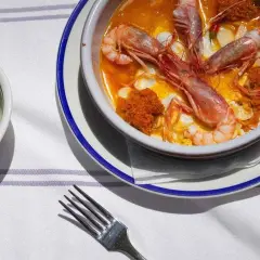 Un plato de gambas en salsa, preparado por un chef del mar, con gajos de lima al lado.