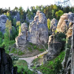 Skalne miasto w Czechach, labirynt piaskowcowych wież i wąskich przejść, otoczony zielenią.