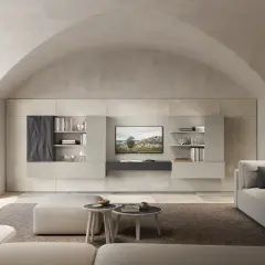 Soggiorno moderno con divano, pouf e parete attrezzata. La **casa color sabbia** è illuminata da un grande lucernario ad arco.