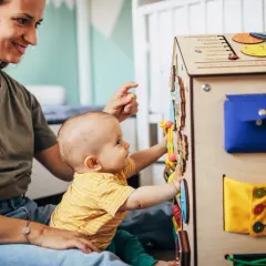 Maluch z radością odkrywa tablicę manipulacyjną. Od jakiego wieku taka zabawka? Od momentu, gdy dziecko zaczyna siedzieć i chwytać.