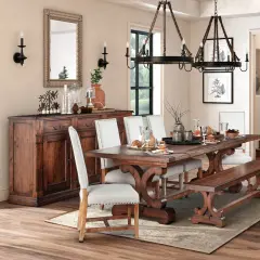 A rustic dining room featuring a dark wood table with ornate legs, upholstered chairs, and a matching bench. This sturdy, beautiful wood is the best wood for kitchen table.