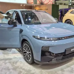 Niebieski SUV z otwartymi drzwiami, prezentujący nowoczesny typ nadwozia. Obok stoi żółty samochód.