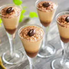 Quattro bicchieri di deliziosa mousse al caffè, spolverata di cacao e guarnita con un chicco di caffè.