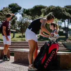 Dziewczyna przygotowuje się do gry w speed badminton, wyjmując buty z torby. W tle widać innych graczy.