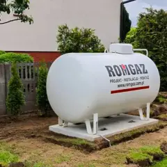 Zbiornik gazu ROMGAZ, kluczowy do określenia, ile metrów sześciennych gazu na ogrzanie domu, stoi na fundamencie w ogrodzie.