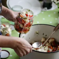 Ręce w fartuchu przygotowują przetwory. Planowanie zakupów warzyw na zimę.