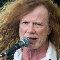 Dave Mustaine young, z burzą rudych włosów i mikrofonem przed ustami, śpiewa na scenie.