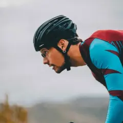 Kolarz w kasku pochyla się nad kierownicą. Prawidłowa pozycja podczas jazdy na rowerze chroni kręgosłup szyjny.