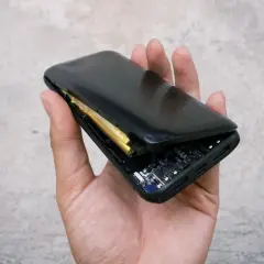 Dłoń trzyma rozłożony powerbank, ukazując spuchniętą baterię i płytkę drukowaną.