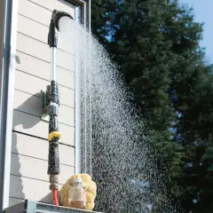Eine Gartendusche, die man selber bauen kann, sprüht erfrischendes Wasser. Ein Schwamm und eine kleine Flasche stehen bereit.