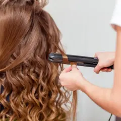 Creando ondas al agua con una plancha. El cabello castaño de una chica se riza, transformándose en suaves ondas.