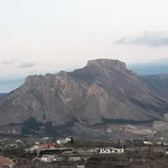 Majestuosa sierra de la Muela con sus picos rocosos y un pequeño pueblo a sus pies.