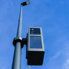 Un radar de ceinture, fixé sur un poteau, surveille la route sous un ciel bleu.