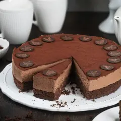Eine köstliche Schoko Torte, bestäubt mit Kakao und verziert mit Schokoladensternen und Rentieren. Ein Stück ist bereits angeschnitten.