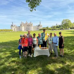 A group enjoys a picnic during their Loire Valley cycling tours, with the magnificent Château de Chambord in the background.