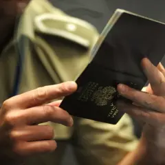 Dłonie trzymają otwarty polski paszport. Czy trzeba oddać stary paszport? Urzędnik sprawdza dokument.