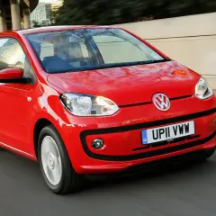 Czerwony Volkswagen up! pędzi ulicą, odbijając światła miasta w swoich lśniących powierzchniach.