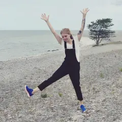 Glad tjej med armarna uppe på en stenig strand på Gotland i Sverige.